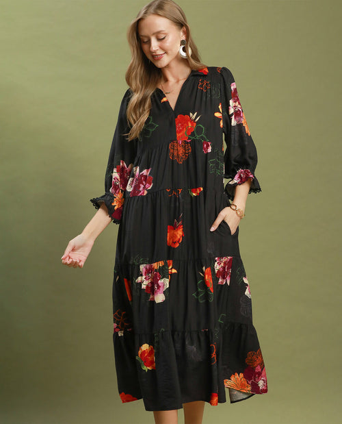 Woman wearing a black dress with colorful floral patterns on an olive green background