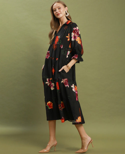 Woman wearing a black floral kimono-style dress on a green background