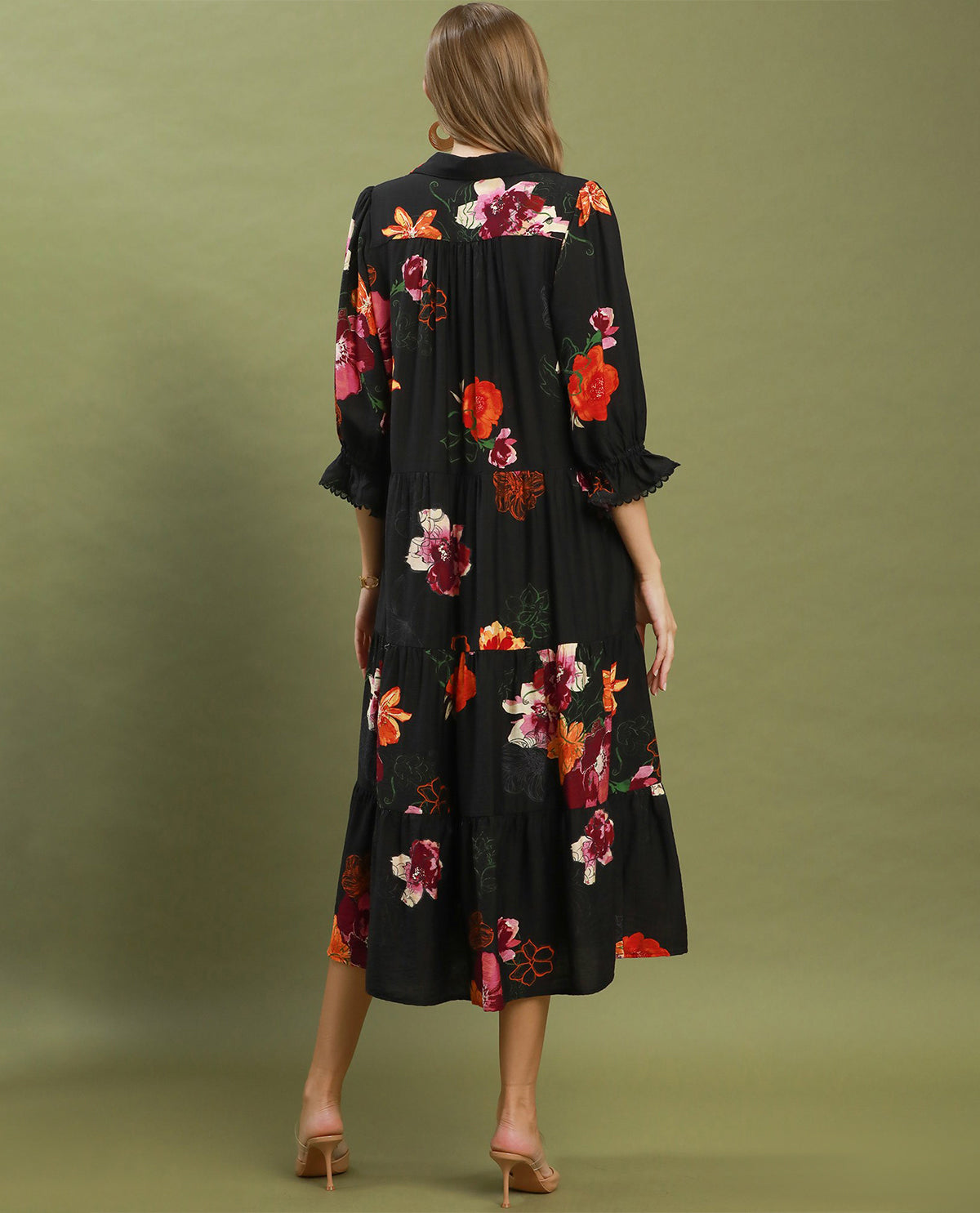 Woman wearing a black floral dress against a green background