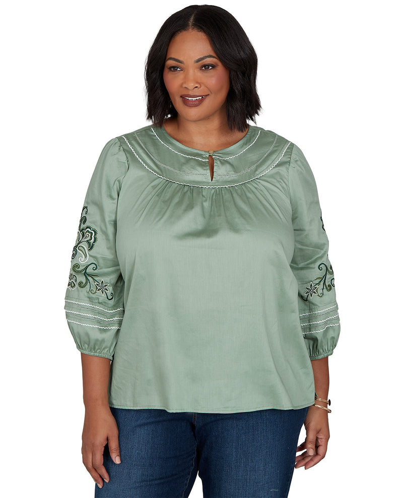 Woman wearing a green blouse with embroidery on a white background