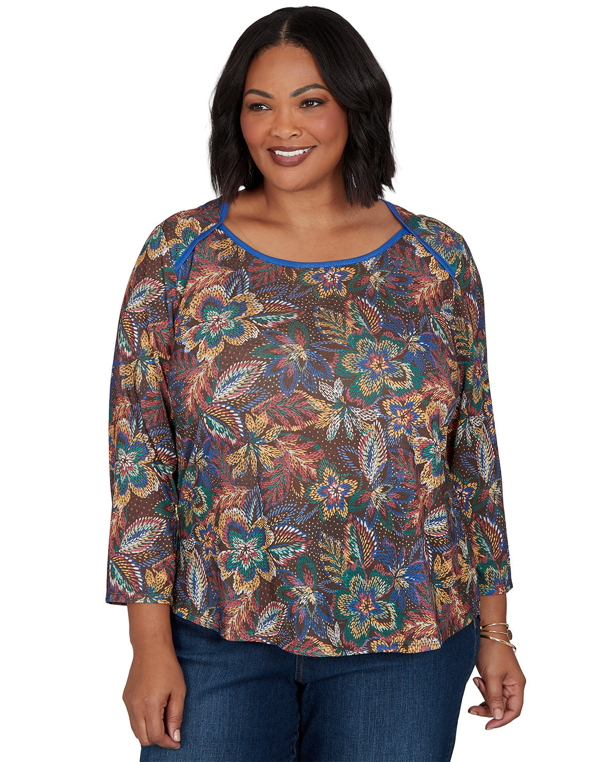 Woman wearing a patterned top with blue jeans on a white background