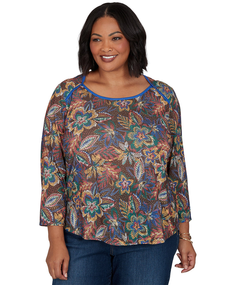 Woman wearing a patterned top with blue jeans on a white background