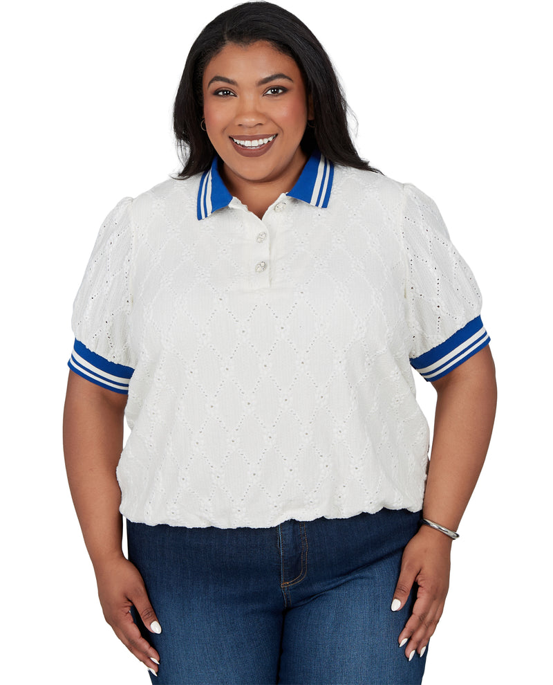 A woman modeling a white eyelet short-sleeve polo shirt with blue and white striped collar and sleeve cuffs, paired with blue jeans against a plain white background.