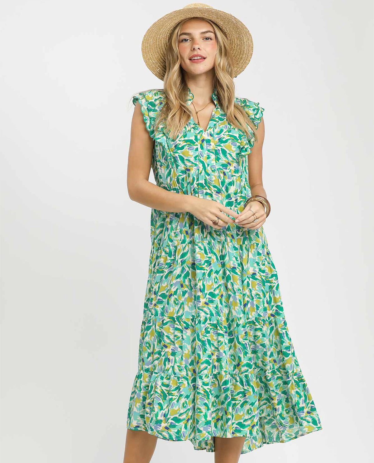 Woman wearing a green floral dress and straw hat on a white background