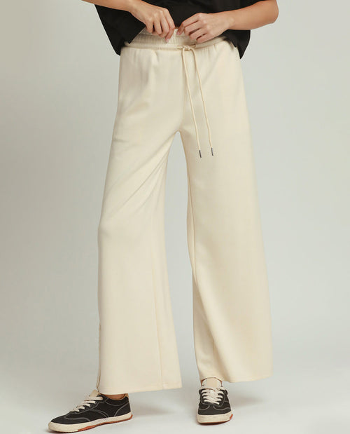 Person wearing beige wide-leg pants with a plain background