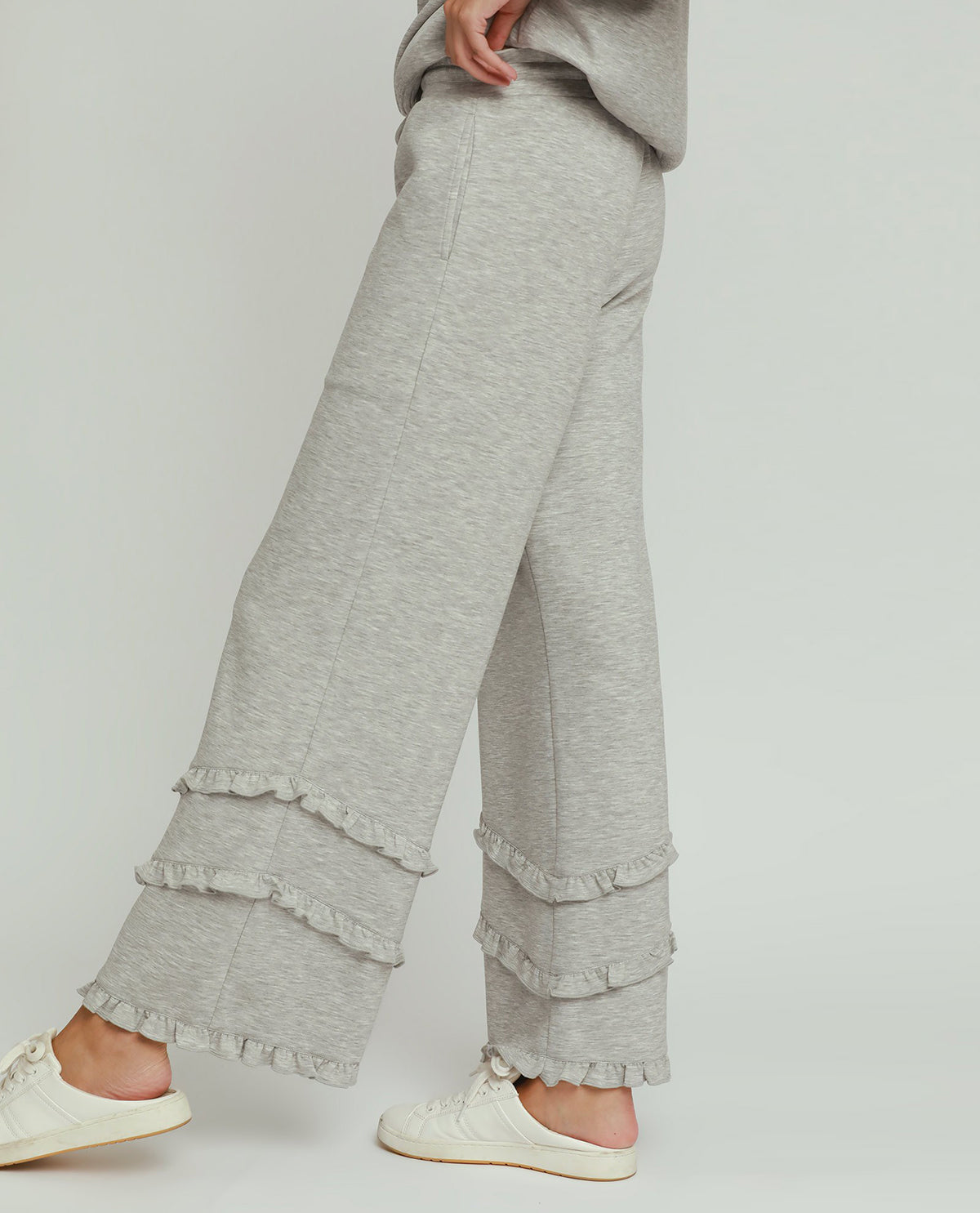 Gray ruffled pants worn by a person on a plain background