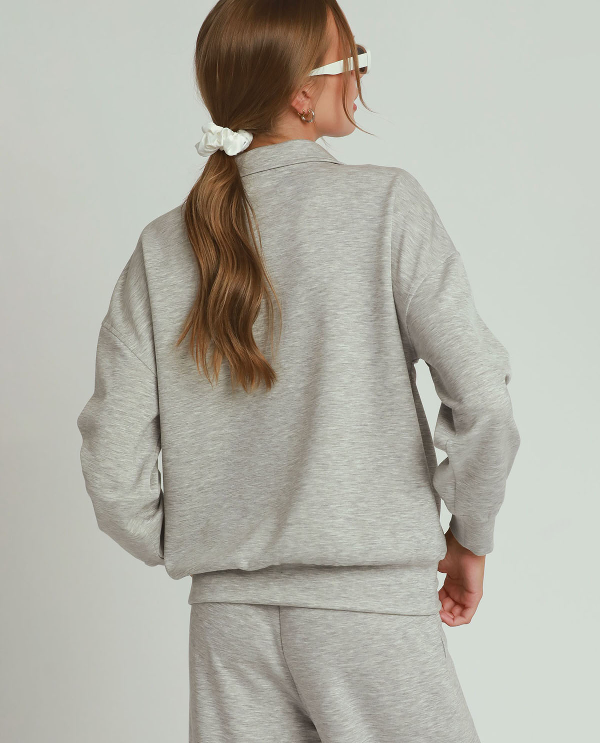 Child wearing a gray tracksuit on a plain background