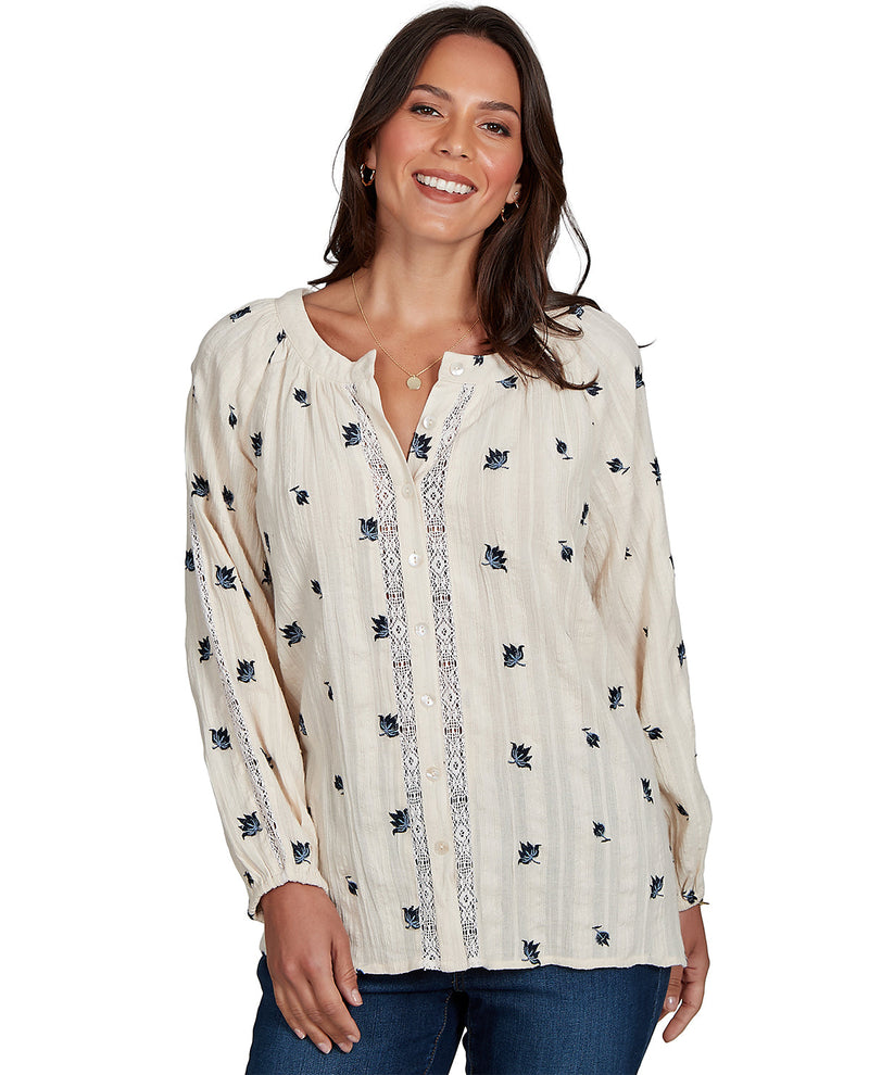 Woman wearing a long-sleeve, patterned blouse on a white background