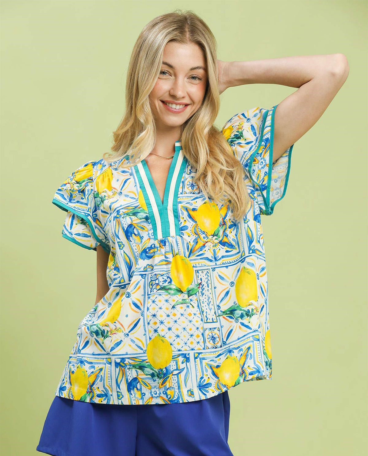Woman wearing a colorful blouse with lemon pattern on a green background