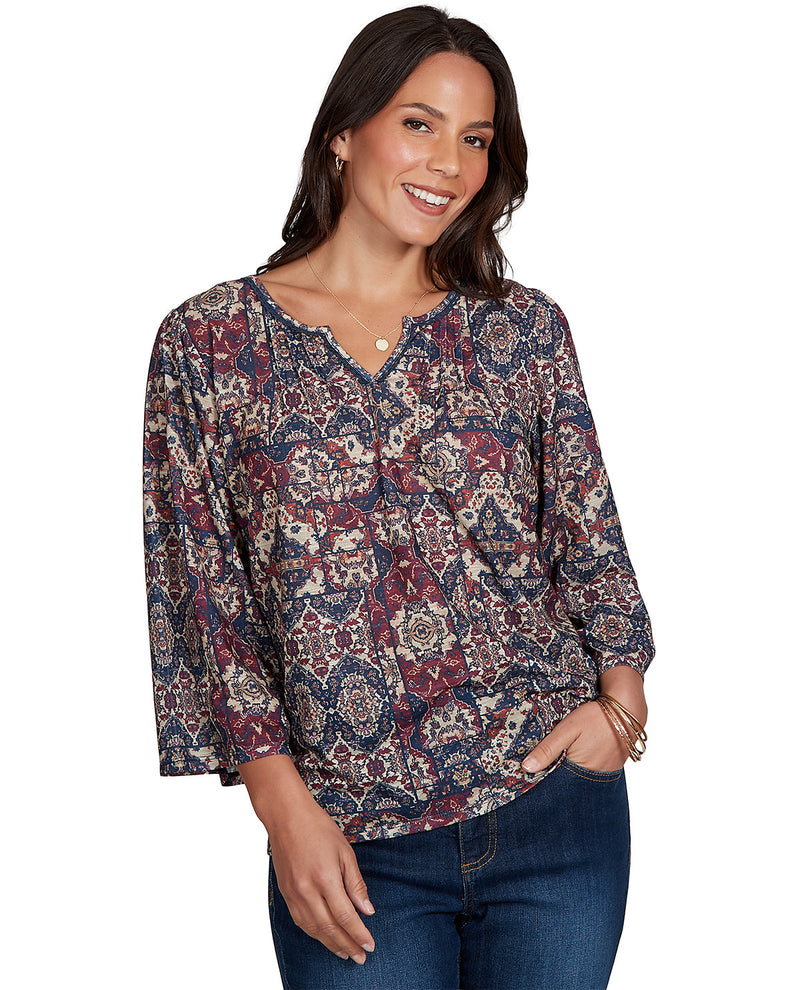 Woman wearing a patterned blouse and jeans on a white background
