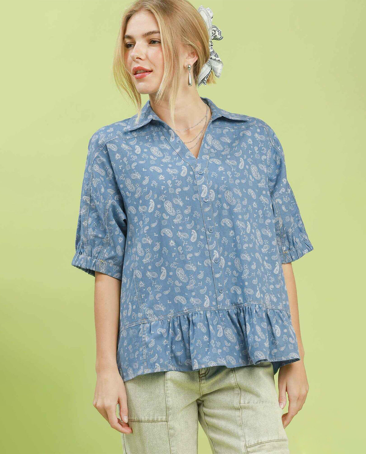 Woman wearing a blue patterned blouse against a green background