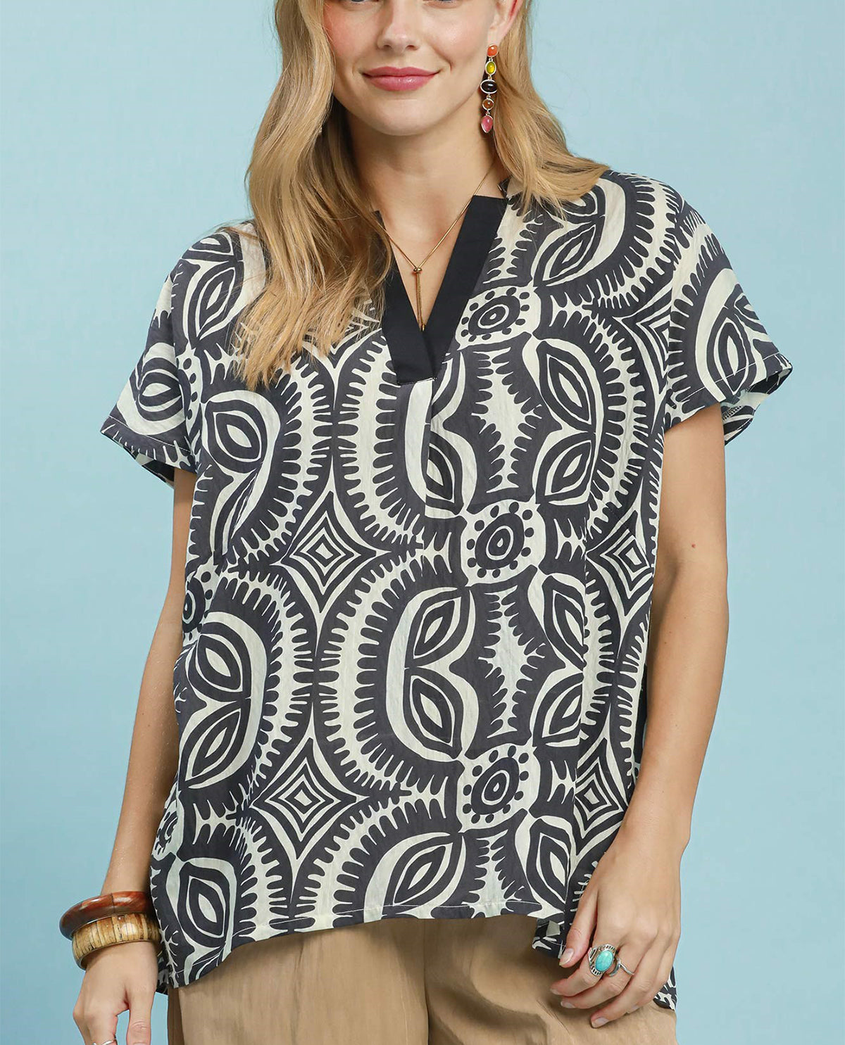 Woman wearing a black and white patterned blouse against a light blue background
