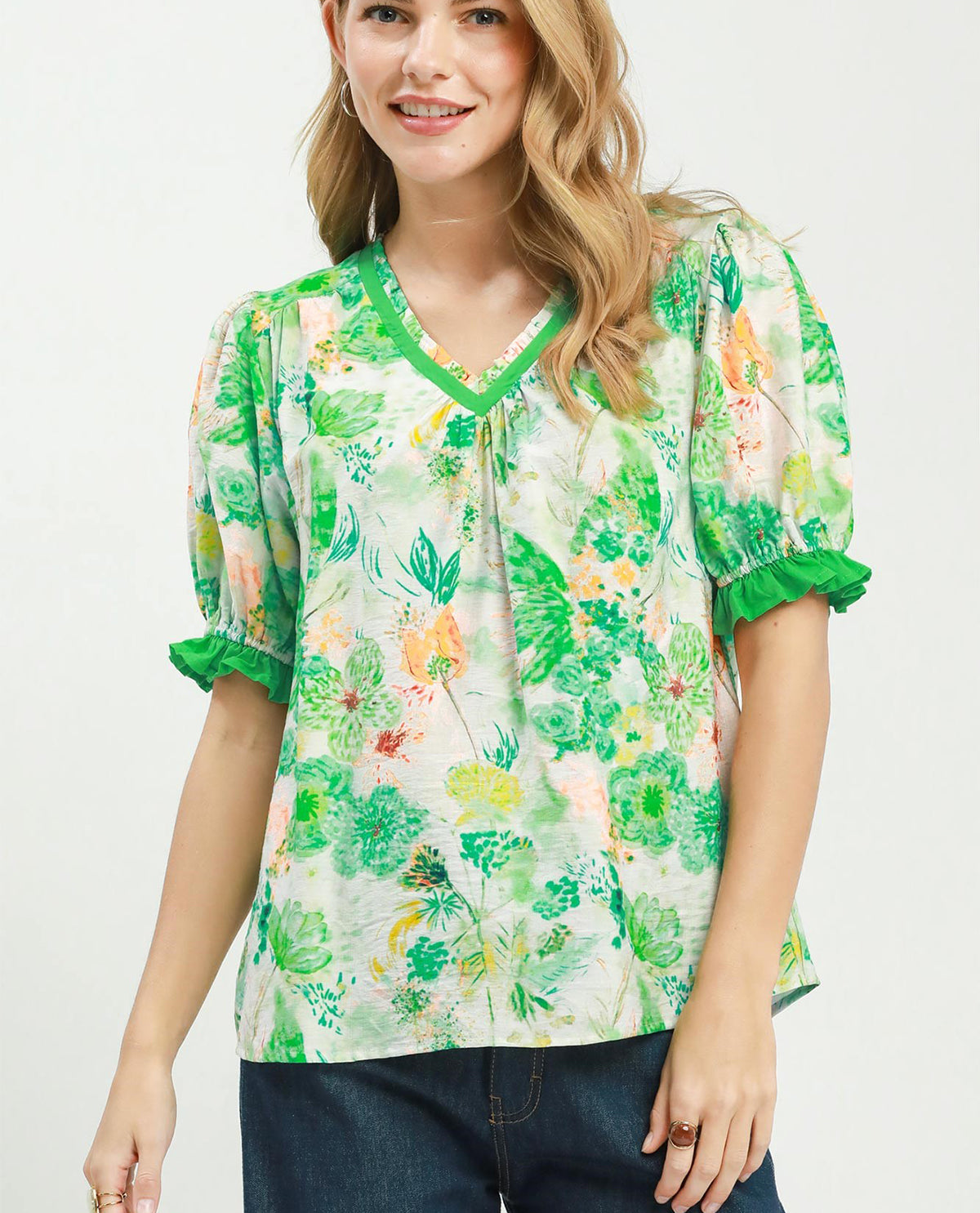 Woman wearing a floral blouse with green accents on a white background