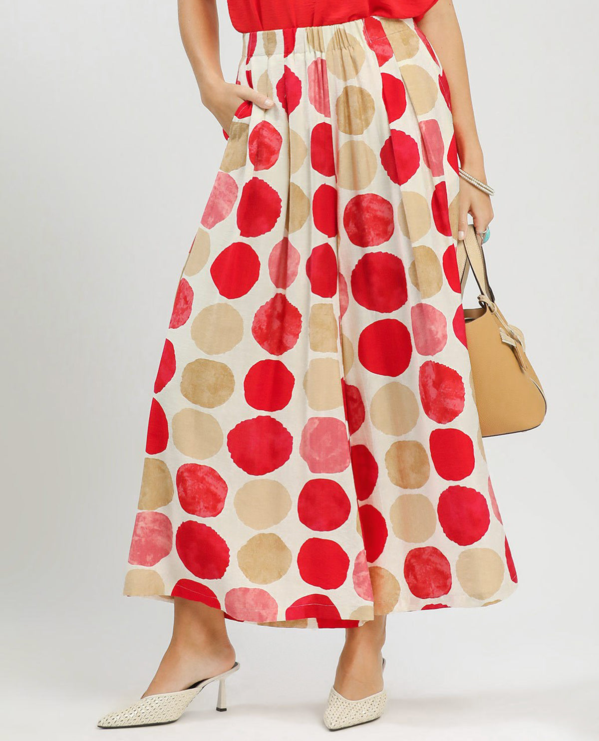 Person wearing a red and beige polka dot skirt with a plain background