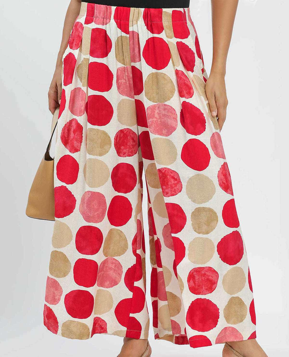 Wide-leg pants with red and beige polka dot pattern on a plain background