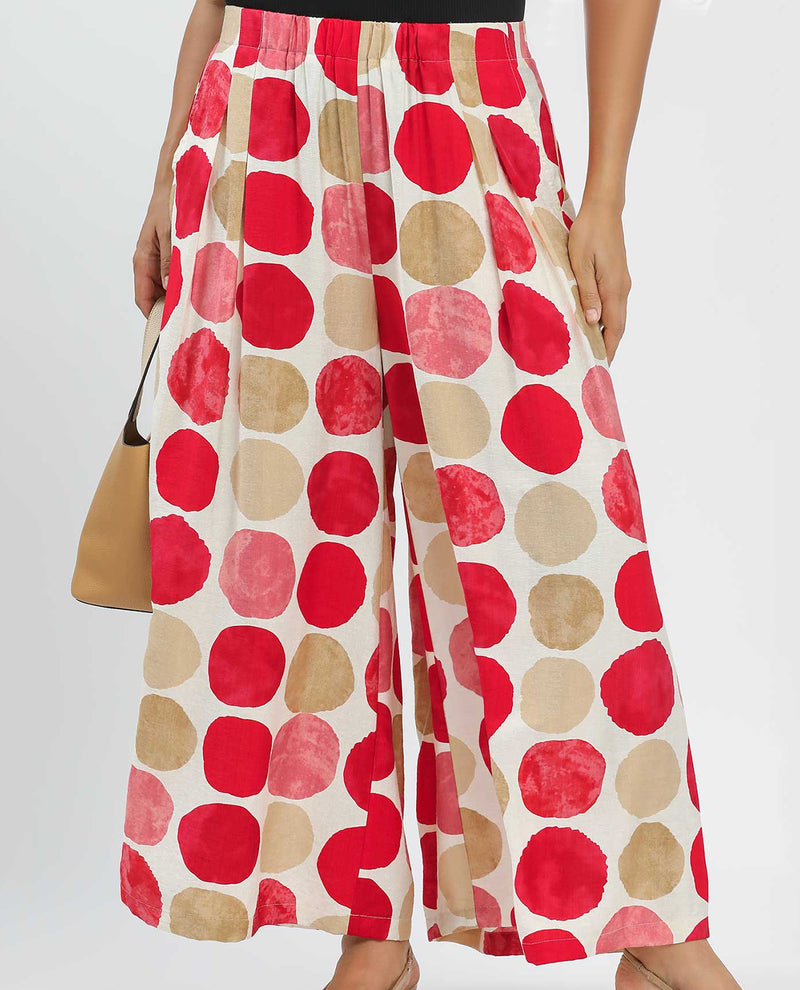 Wide-leg pants with red and beige polka dot pattern on a plain background