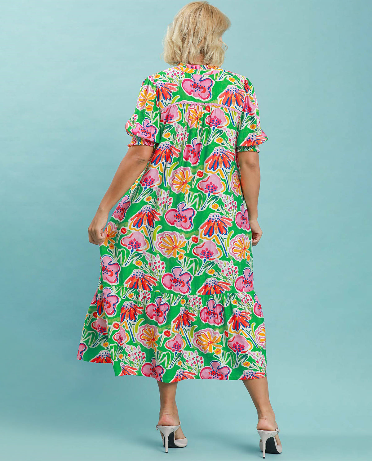 Woman wearing a colorful floral dress against a light blue background