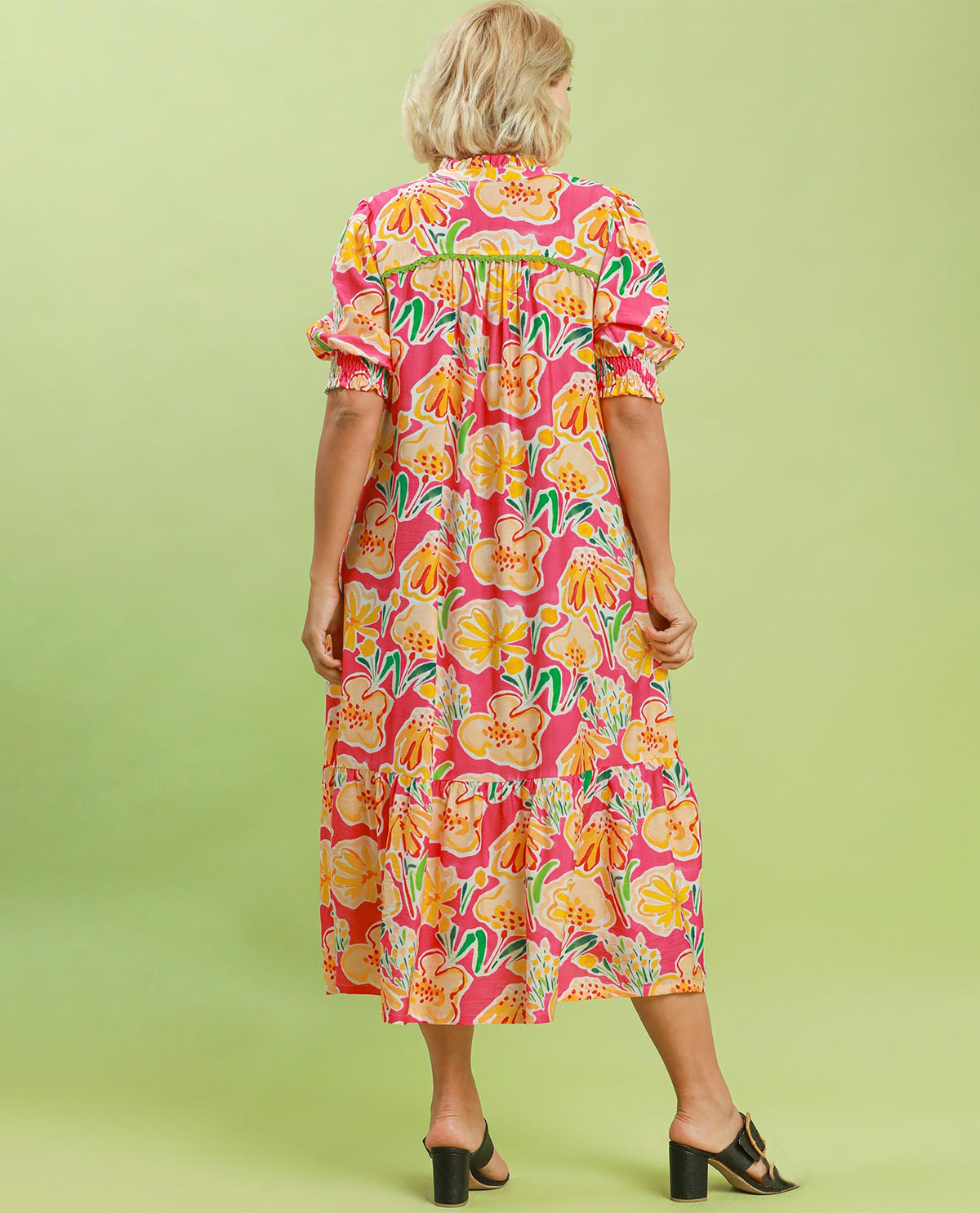 Woman wearing a colorful floral dress on a green background