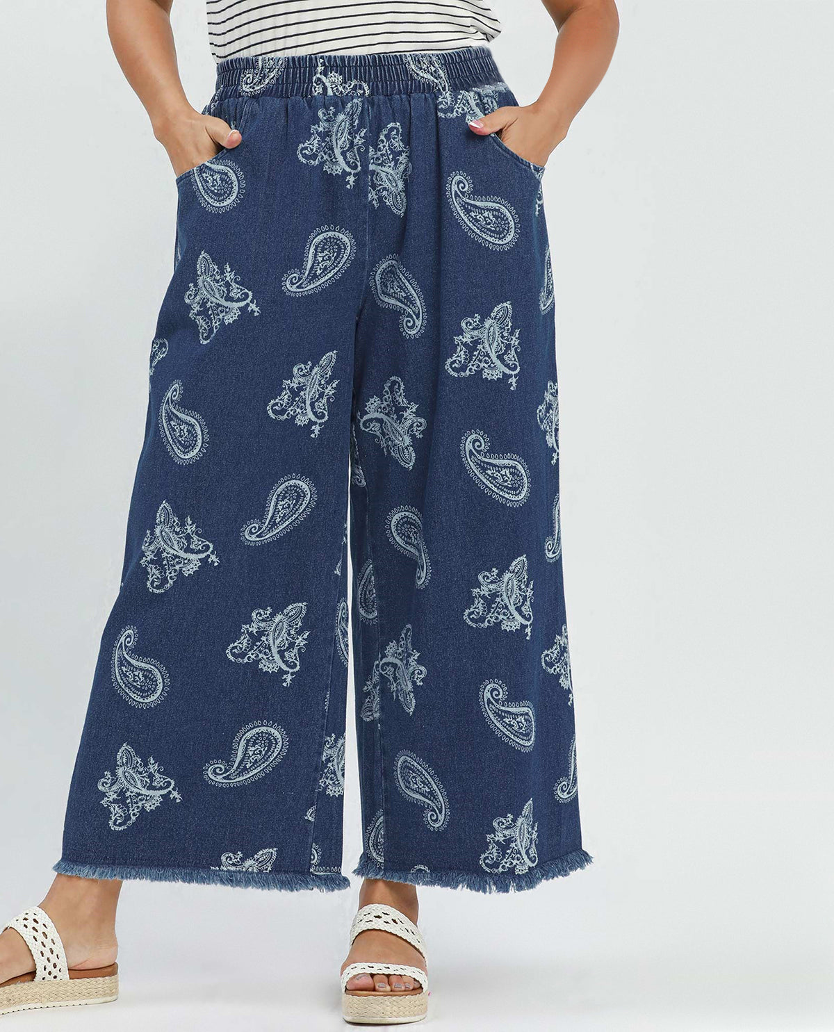Person wearing blue paisley-patterned pants on a white background