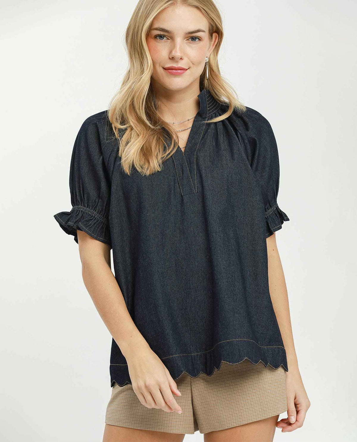 Woman wearing a dark denim blouse with rolled-up sleeves on a white background
