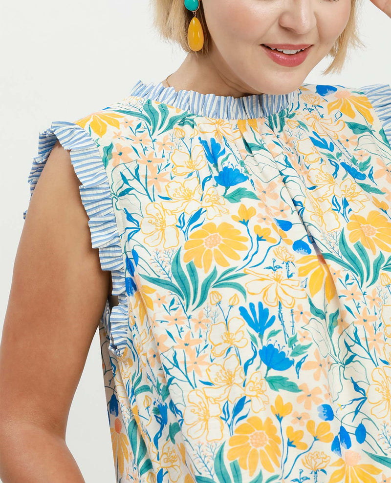 Woman wearing a floral dress with yellow and blue flowers on a white background