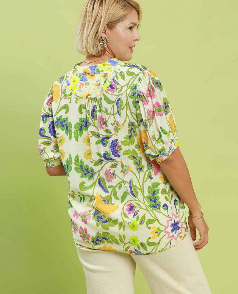 Woman wearing a colorful floral blouse against a light green background