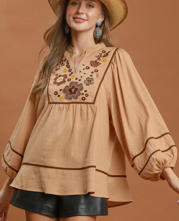 Woman wearing a beige embroidered blouse with a brown background