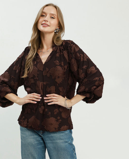 Woman wearing a brown floral blouse and blue jeans on a white background