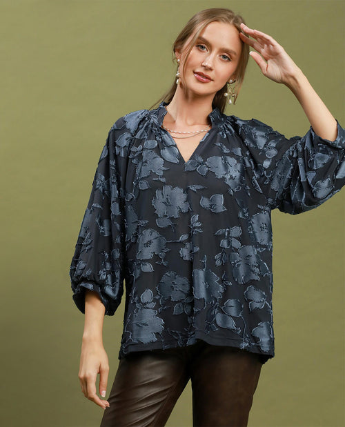 Woman wearing a dark floral blouse against an olive green background