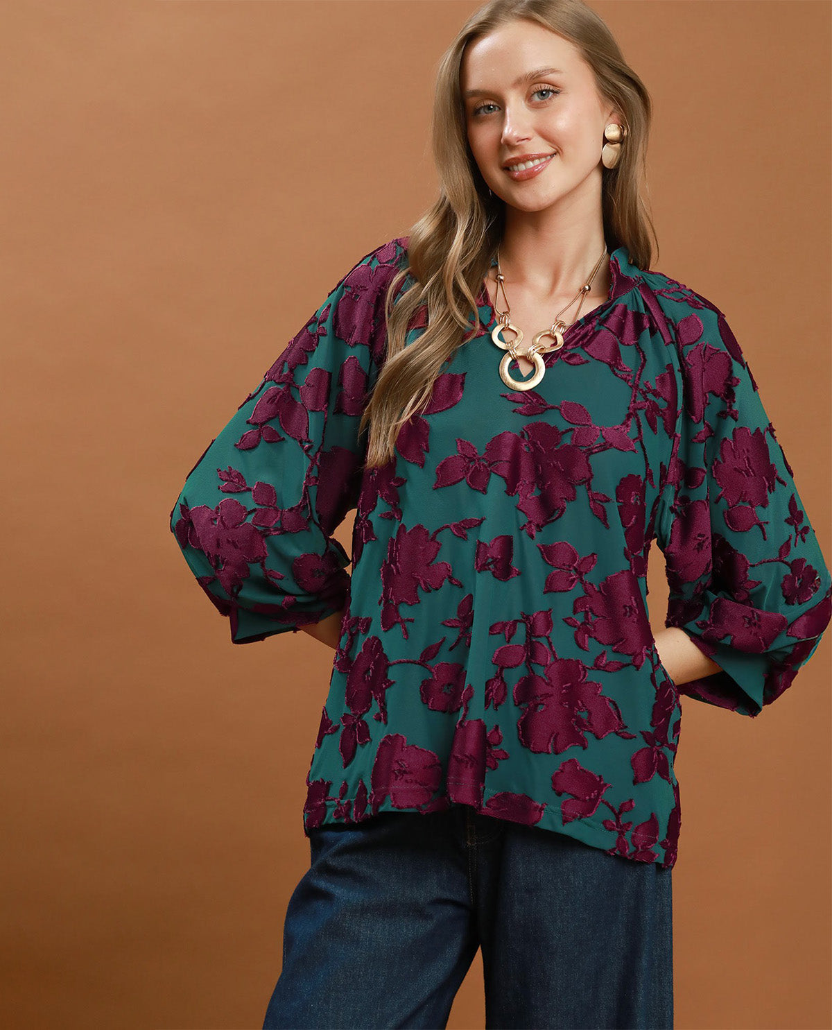 Woman wearing a green floral blouse against a brown background