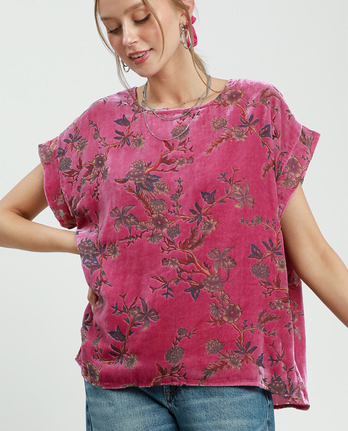 Woman wearing a pink floral top with a plain background