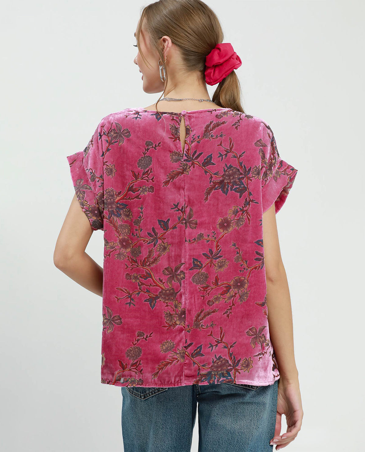 Woman wearing a pink floral blouse with a plain background