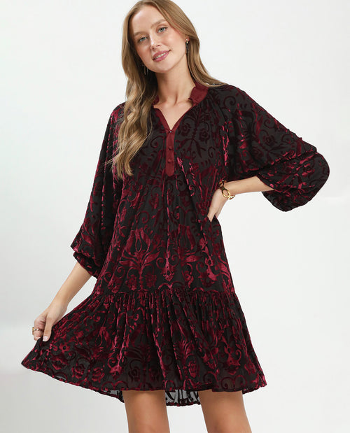 Woman wearing a red and black patterned dress on a white background