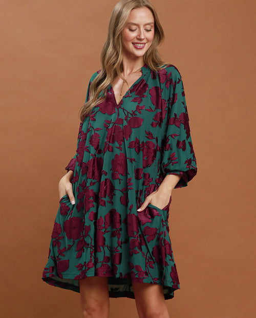 Woman wearing a green and purple floral dress against a brown background