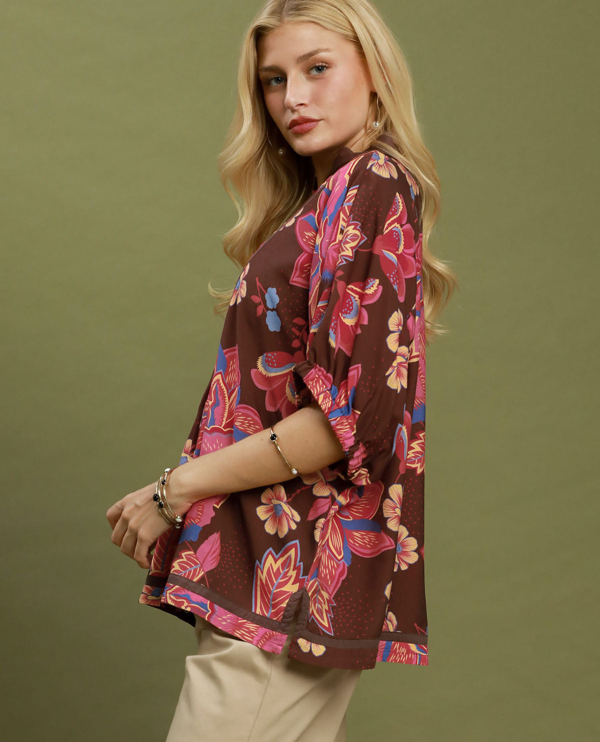 Woman wearing a floral kimono-style top against a green background