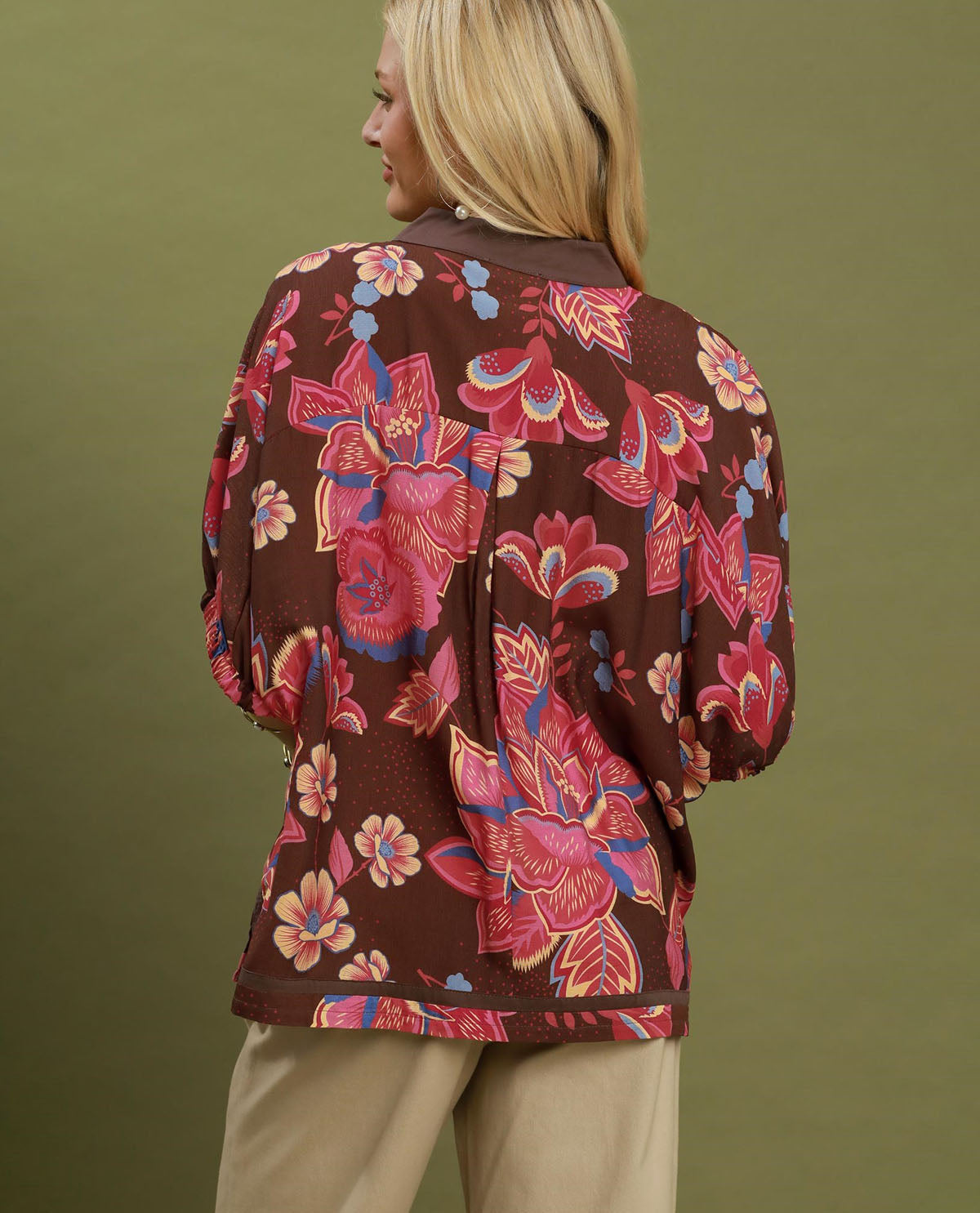 Woman wearing a brown floral jacket against a green background