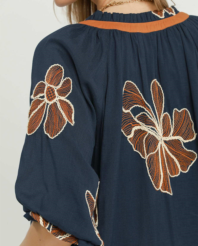 Navy blue blouse with brown floral embroidery on a plain background