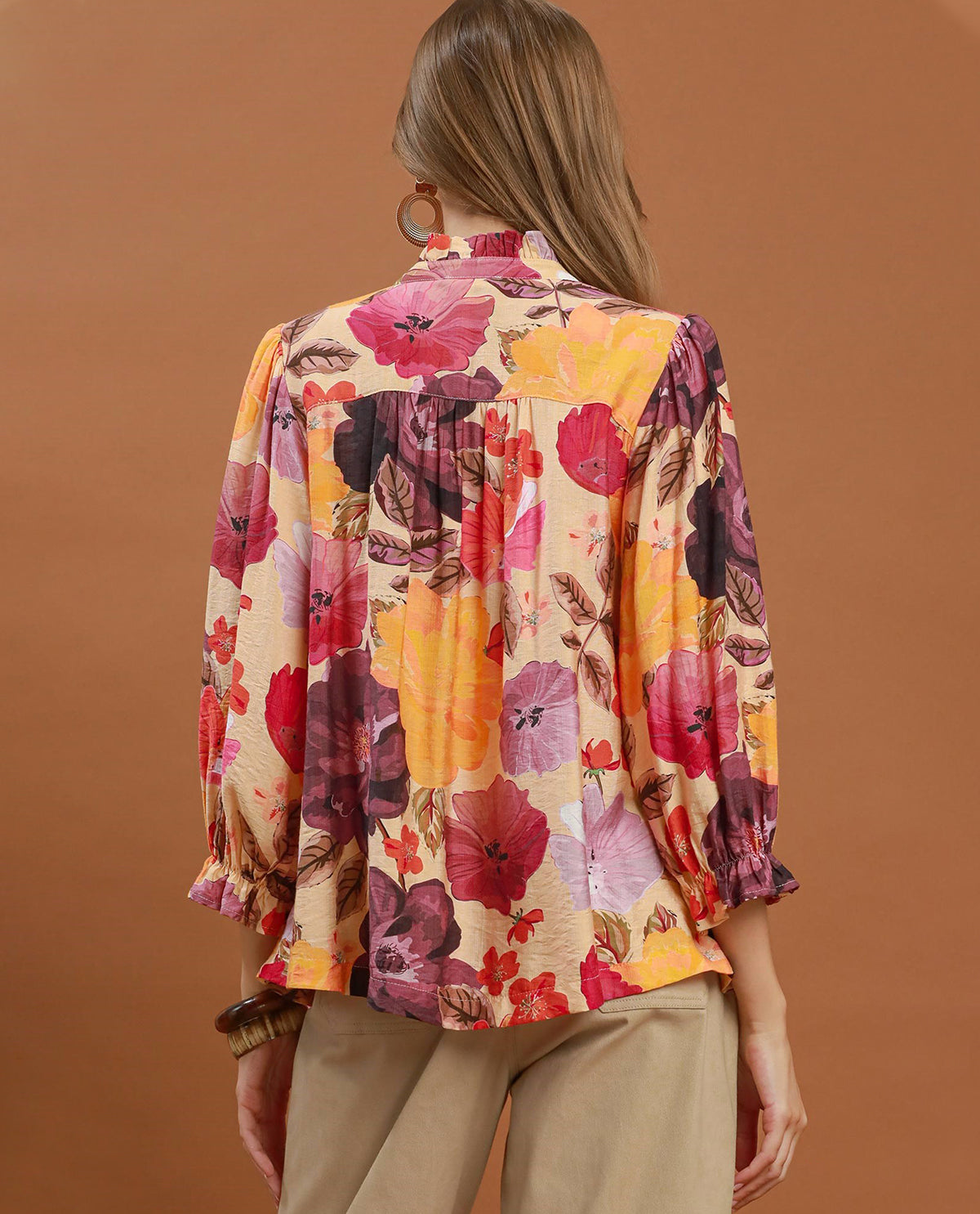 Woman wearing a colorful floral blouse against a brown background