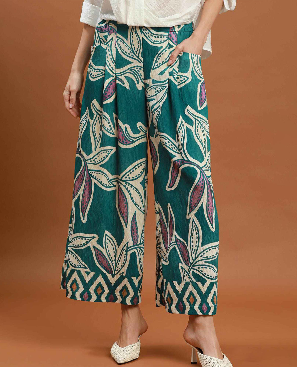 Person wearing teal patterned pants on a brown background