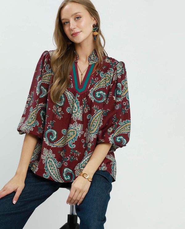 Woman wearing a patterned blouse with a plain background