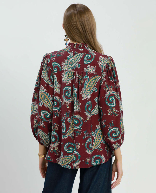 Woman wearing a patterned blouse with a plain background