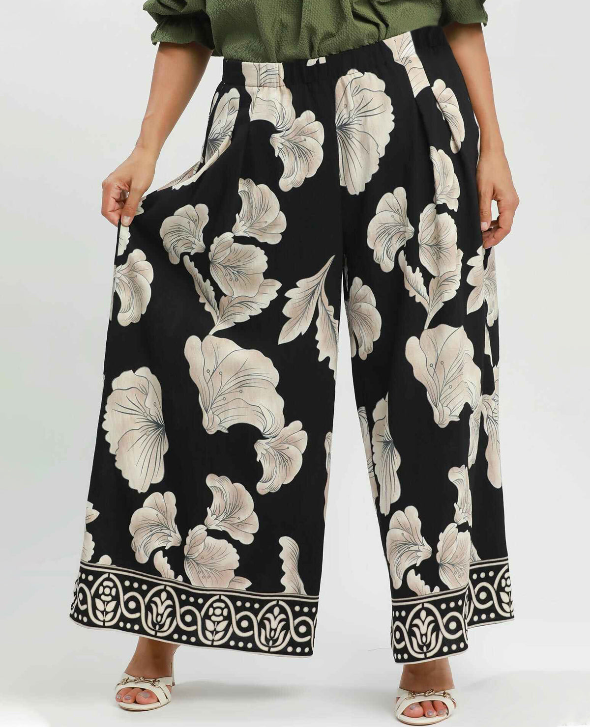 Person wearing black floral-patterned pants on a white background
