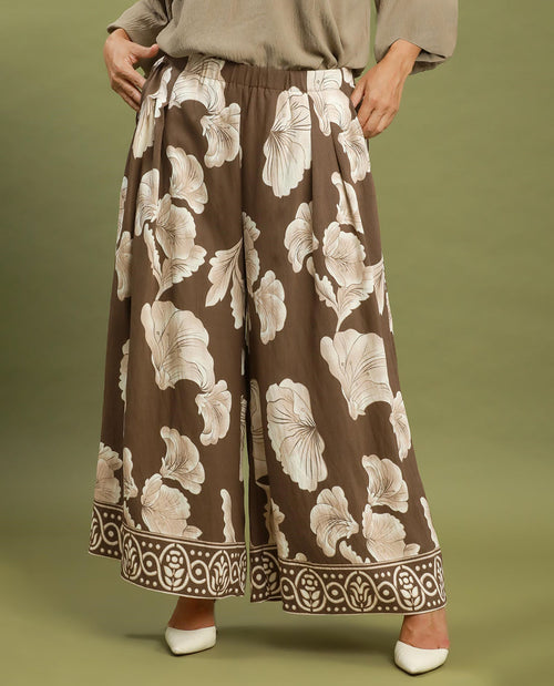 Floral patterned pants on a person against an olive green background