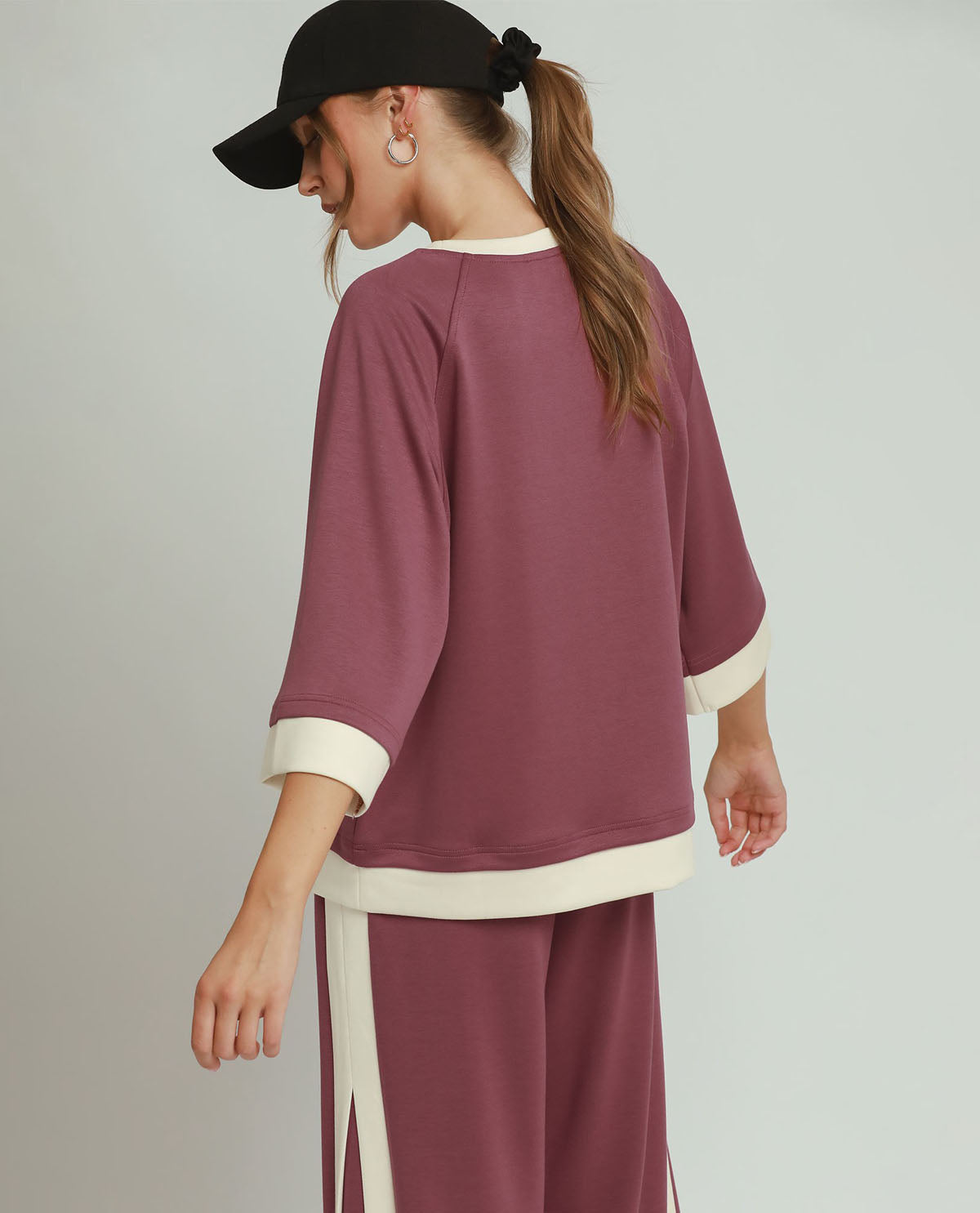 Person wearing a maroon outfit with white accents on a plain background