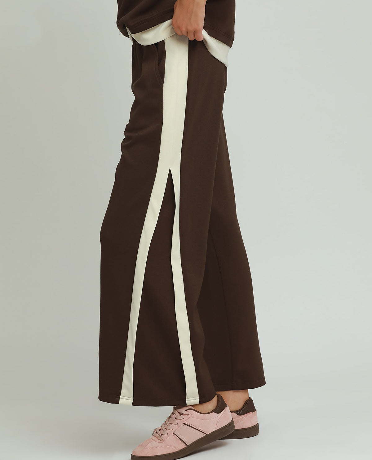 Brown pants with white stripes worn by a person on a light gray background
