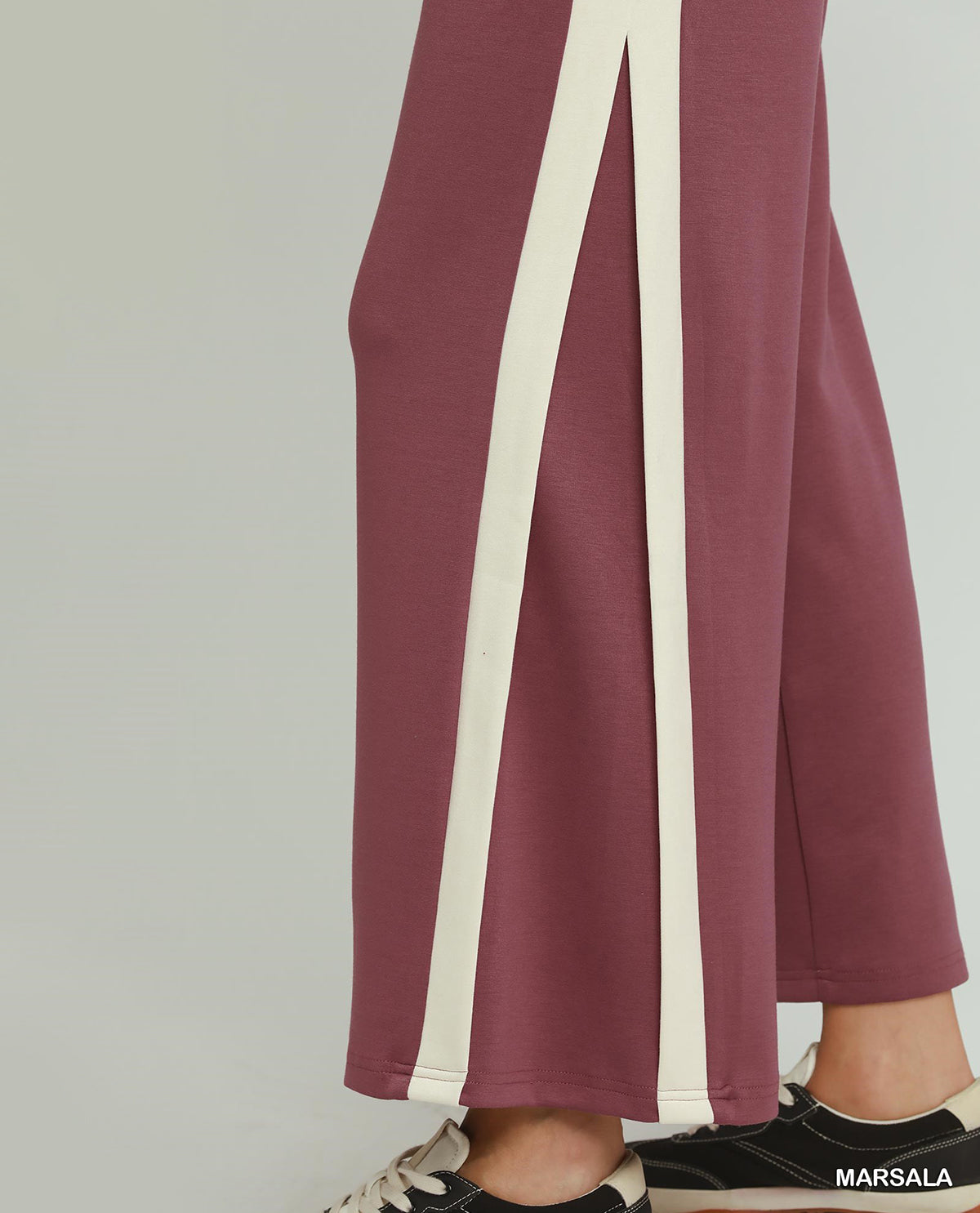 Maroon pants with white stripes worn by a person on a gray background