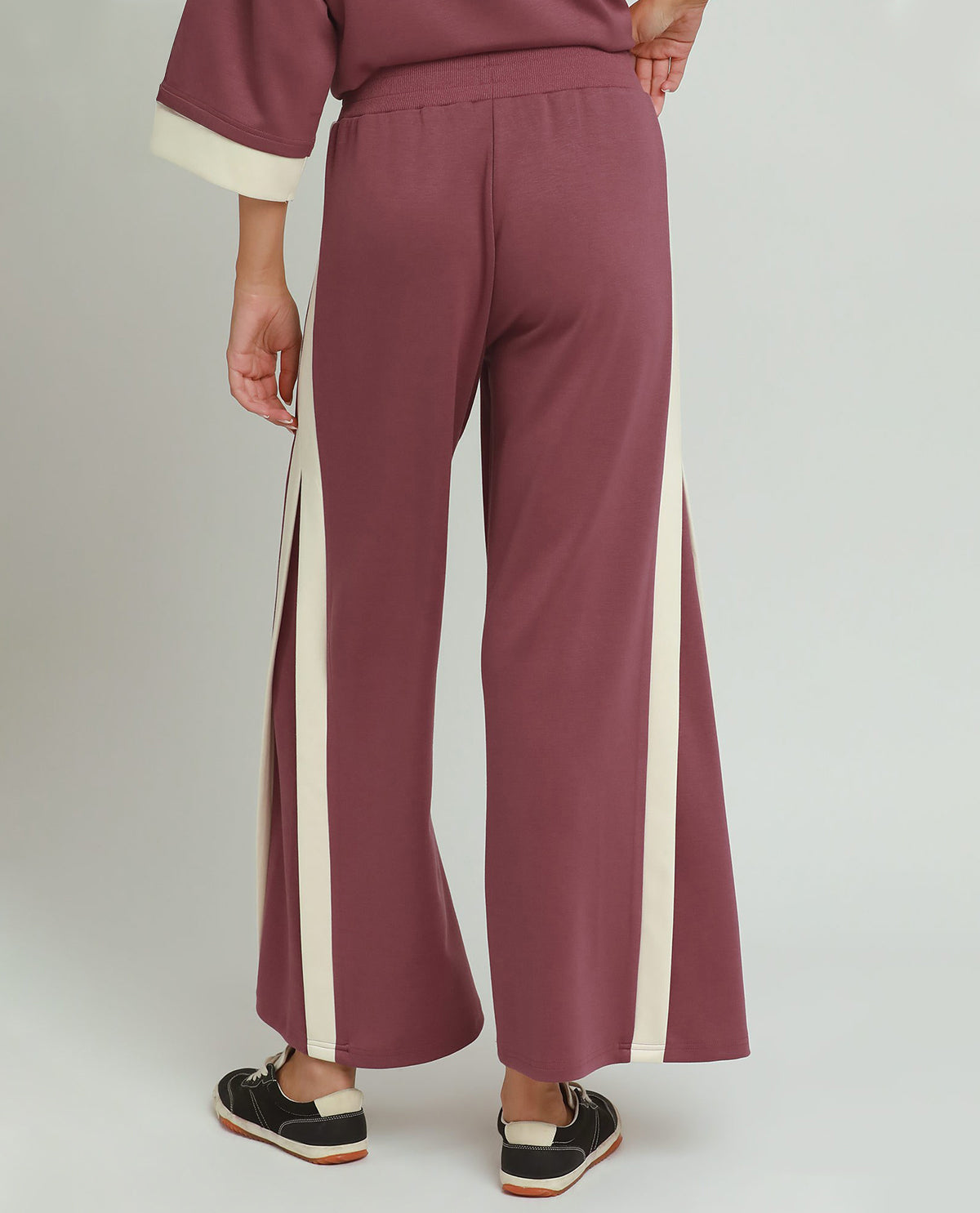 Maroon pants with white side stripes worn by a person on a plain background
