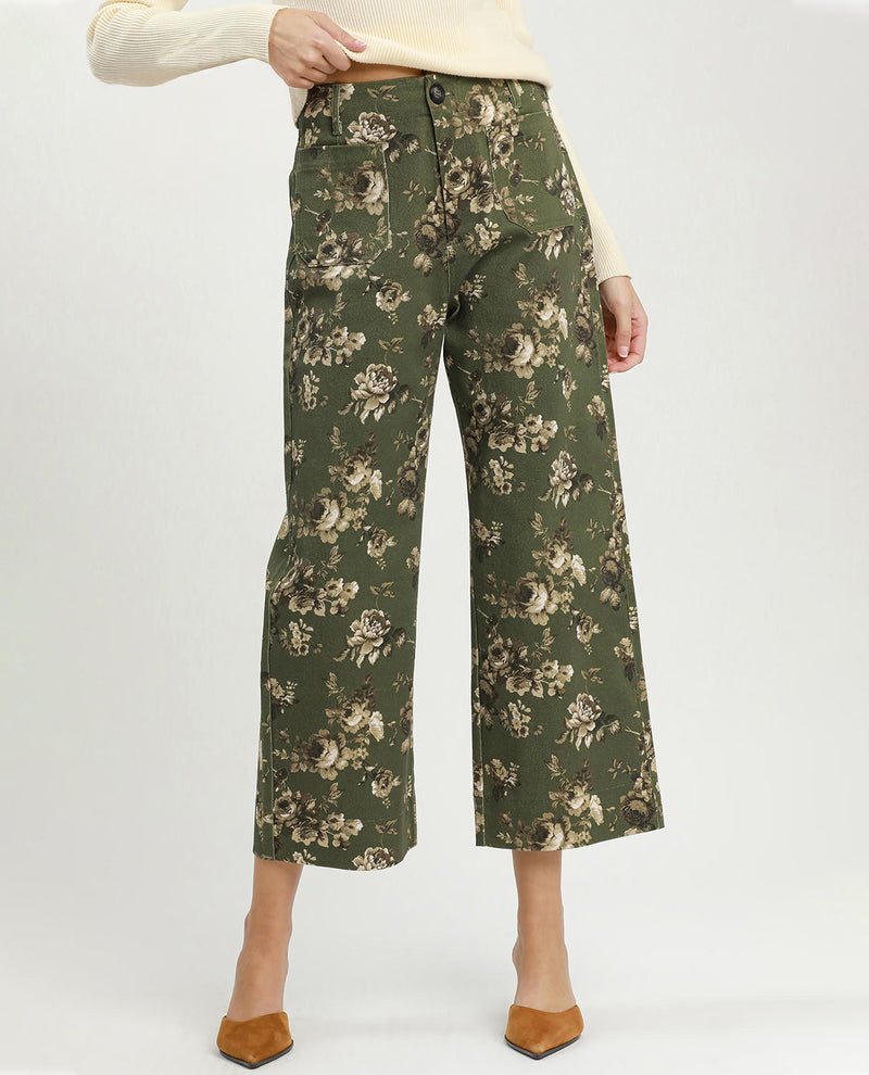 Green floral-patterned pants worn by a person on a white background