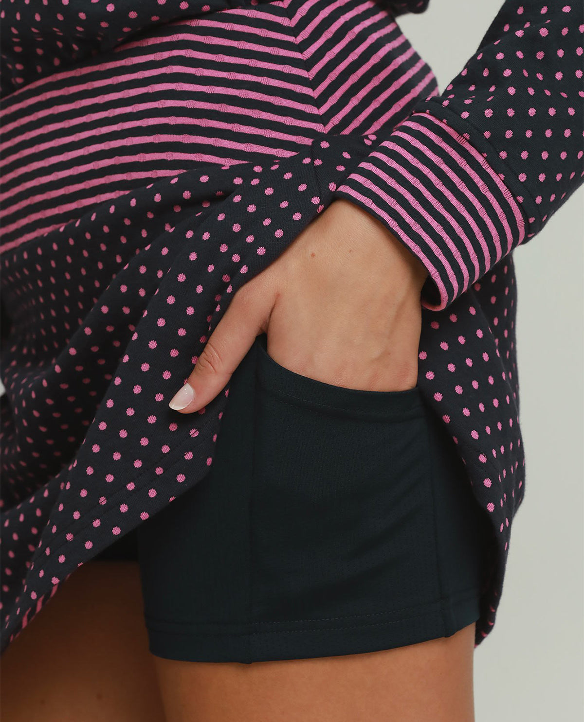 Person wearing a black and pink striped shirt with a polka dot pattern, paired with black shorts.