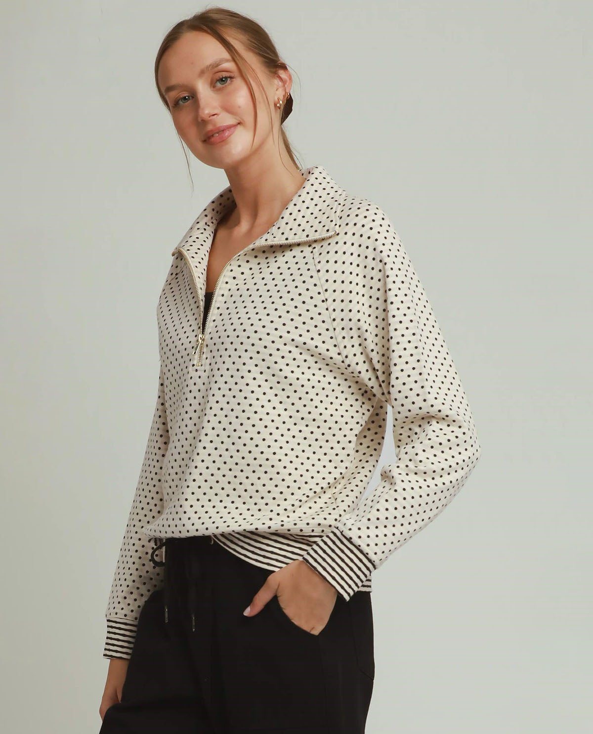 Woman wearing a polka dot jacket with a plain background